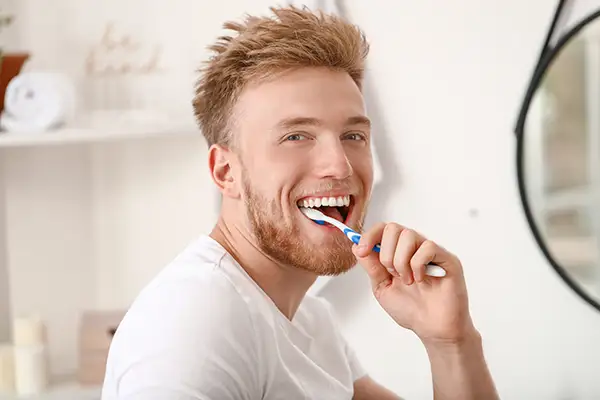 Smiling man brushing his teeth in a modern bathroom, promoting dental hygiene for a healthy smile. Smiling man brushing his teeth in a modern bathroom, promoting dental hygiene for a healthy smile.