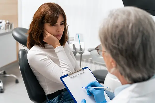 Female patient consulting with a dentist about severe tooth pain during an emergency dental appointment in a clinic. Female patient consulting with a dentist about severe tooth pain during an emergency dental appointment in a clinic.