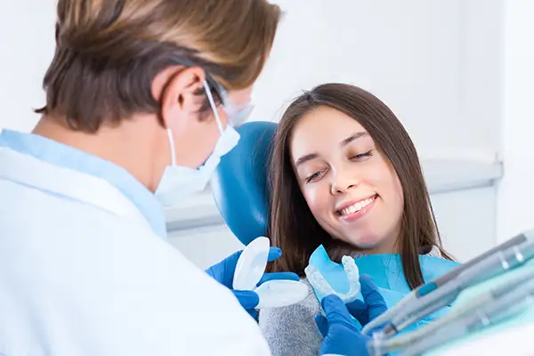 Dentist presenting mouth guard options to a smiling patient during a dental consultation. Dentist presenting mouth guard options to a smiling patient during a dental consultation.