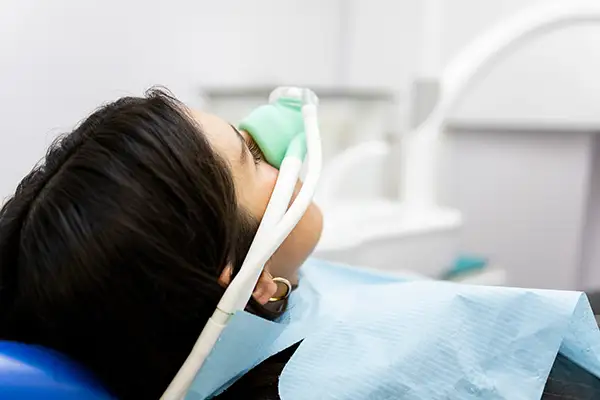 Patient receiving nitrous oxide sedation through a mask during a dental procedure. Patient receiving nitrous oxide sedation through a mask during a dental procedure.